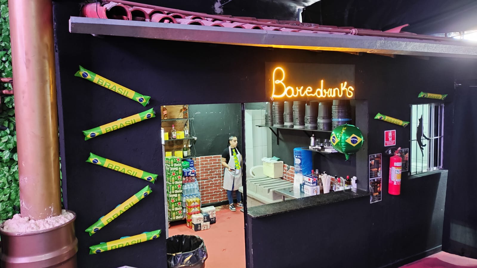 Bar e drinks da Villa em clima de Copa com bandeiras do Brasil e neon